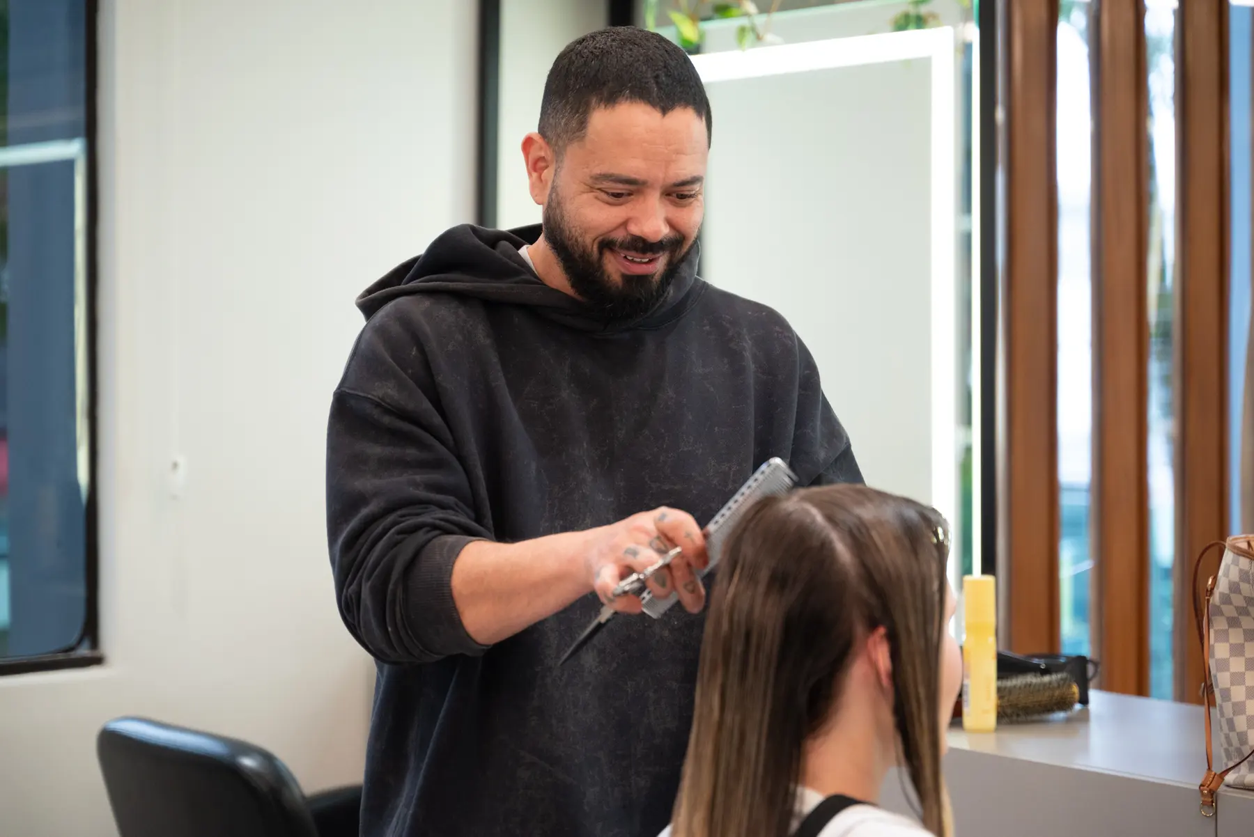 Cabeleireiro avaliando o rosto da cliente antes do corte, no salão Colonialle no Batel